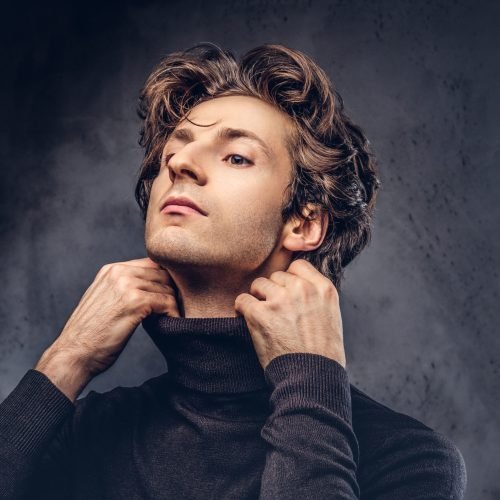 Portrait of a charismatic sensual male in black sweater. Creative personality.