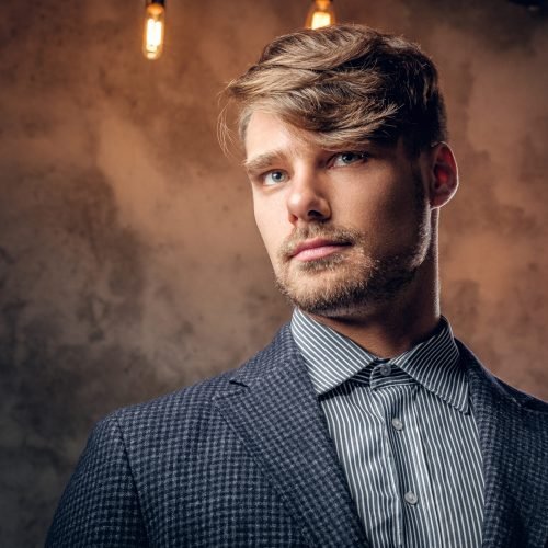 Portrait of stylish maledressed in a suit over grey background.